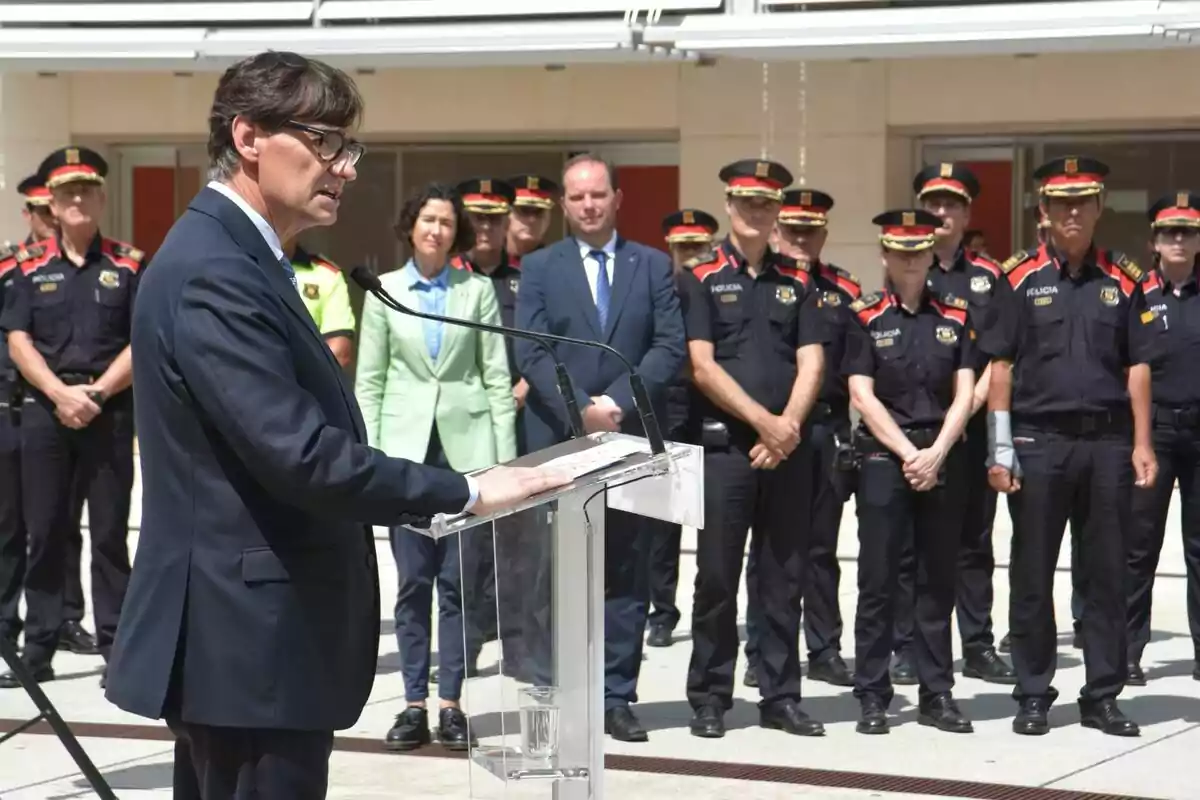 Salvador Illa en un podio hablando frente a un grupo de policías.