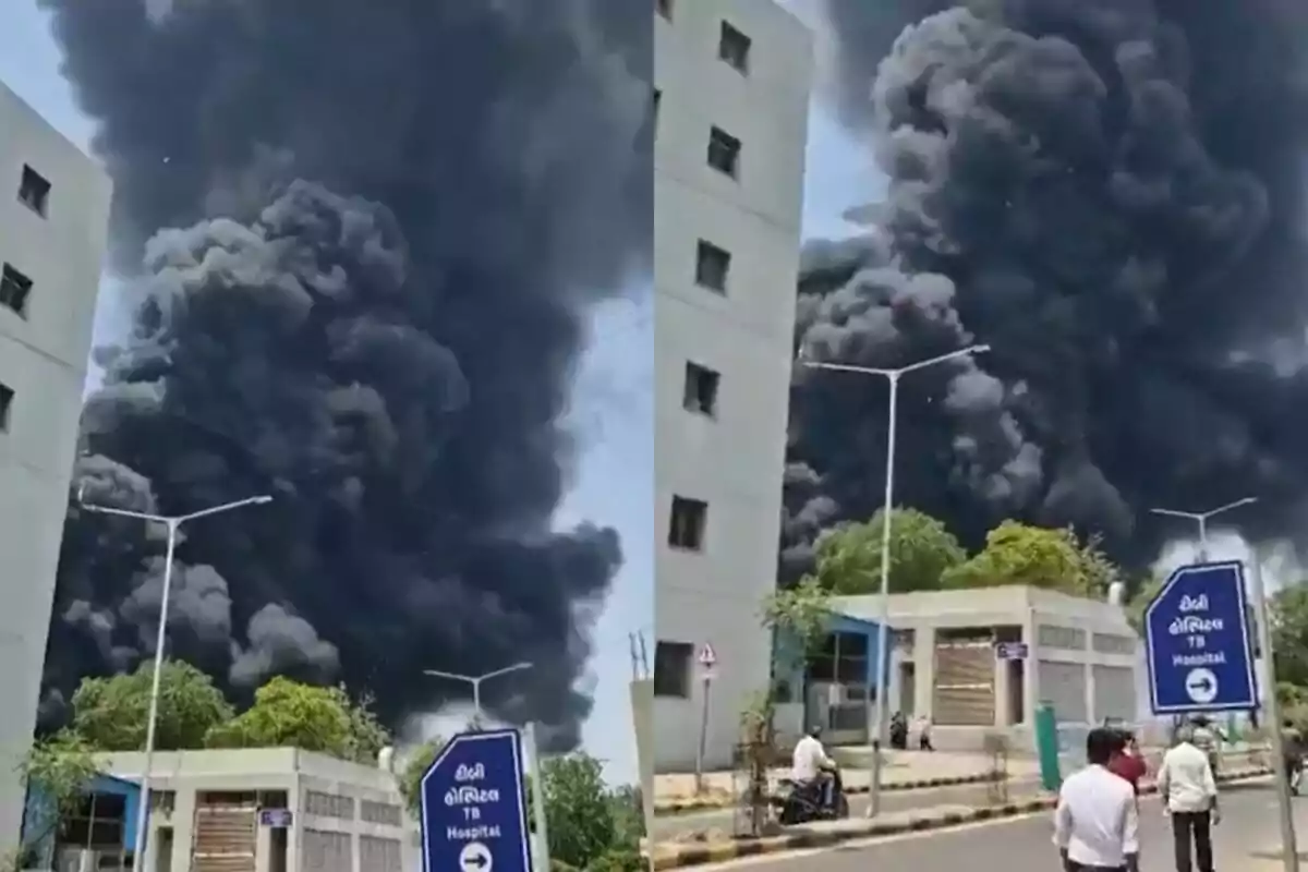 Gran columna de humo negro se eleva detrás de un edificio mientras varias personas observan la escena desde la calle Gran columna de humo negro se eleva detrás de un edificio mientras varias personas observan la escena desde la calle