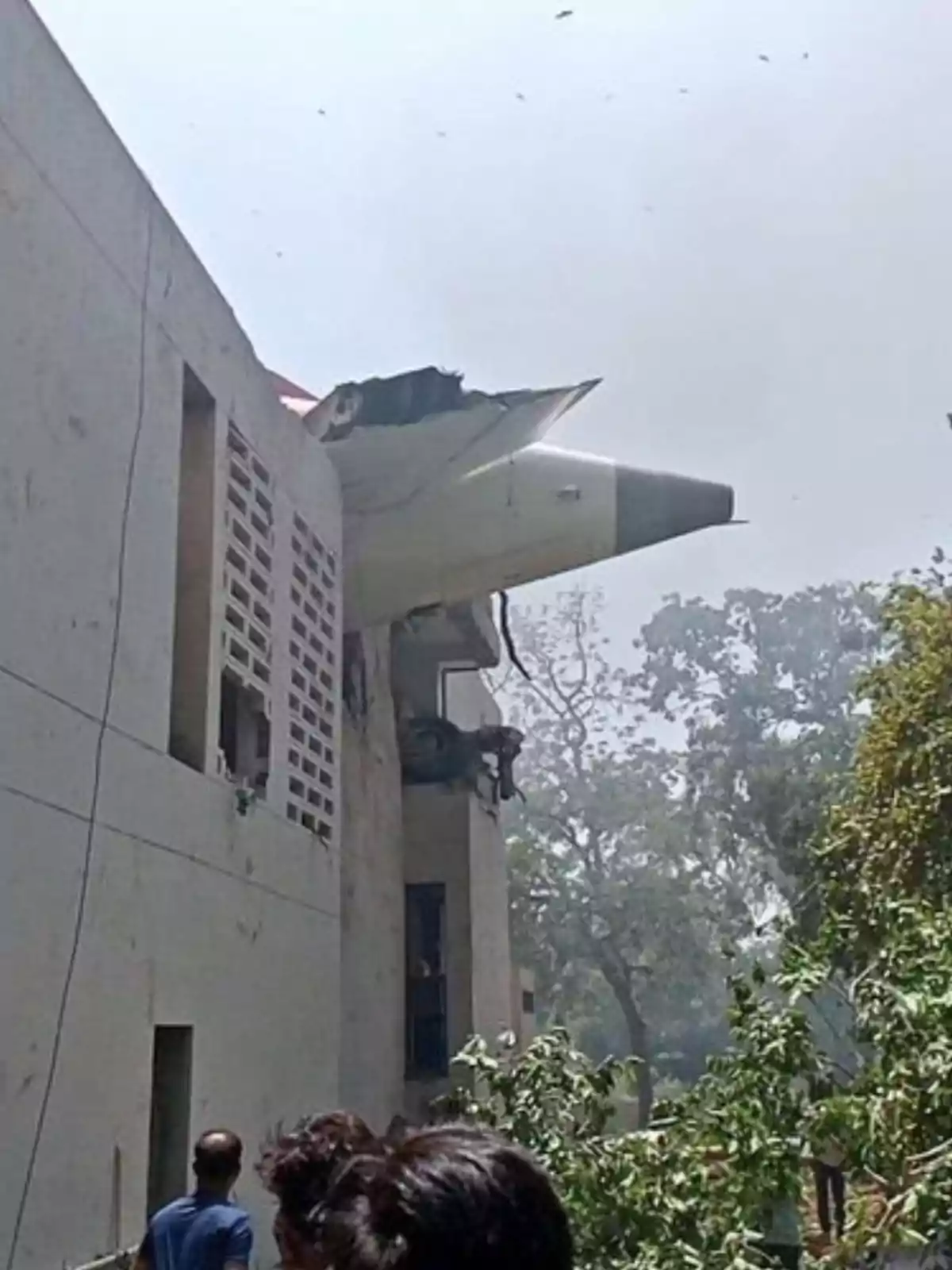 Un avión se ha estrellado contra un edificio y parte de la aeronave sobresale de la estructura mientras varias personas observan desde abajo Un avión se ha estrellado contra un edificio y parte de la aeronave sobresale de la estructura mientras varias personas observan desde abajo