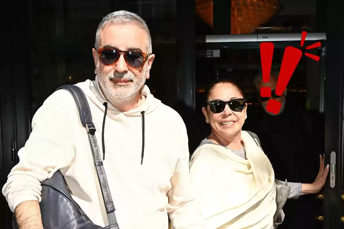 Agustín Pantoja e Isabel Pantoja con gafas de sol sonriendo mientras salen de un edificio.