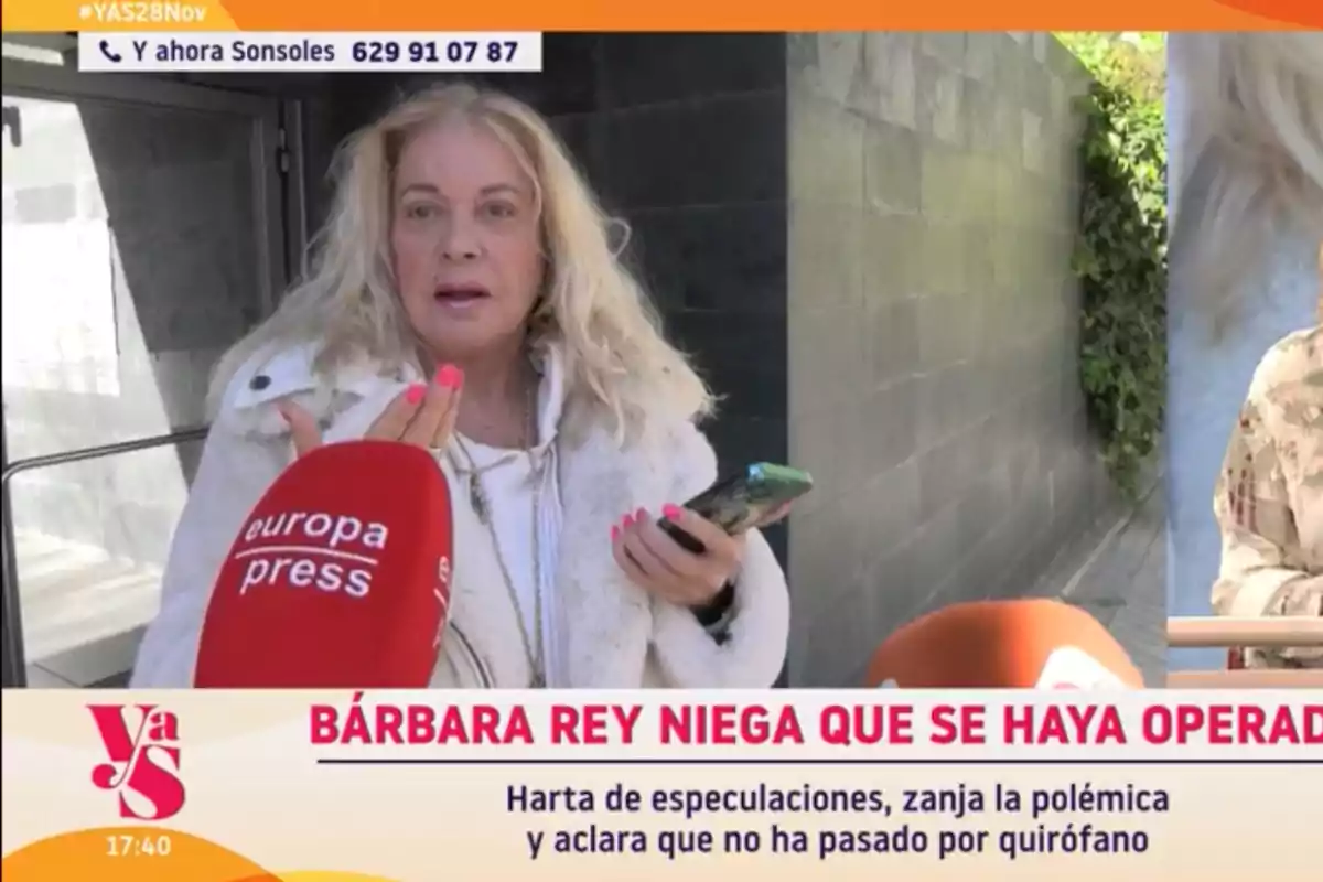 Bárbara Rey con cabello rubio sostiene un teléfono móvil mientras es entrevistada por un medio de comunicación. Bárbara Rey con cabello rubio sostiene un teléfono móvil mientras es entrevistada por un medio de comunicación.