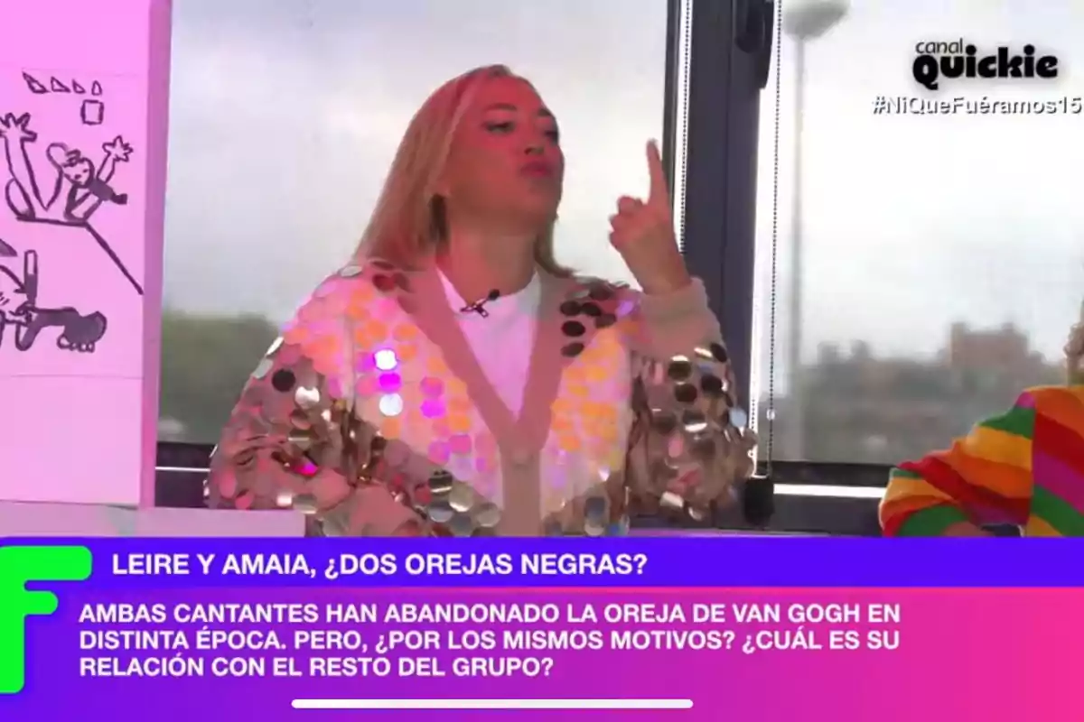 Belén Esteban con un suéter de lentejuelas está gesticulando con la mano mientras participa en un programa de televisión llamado 