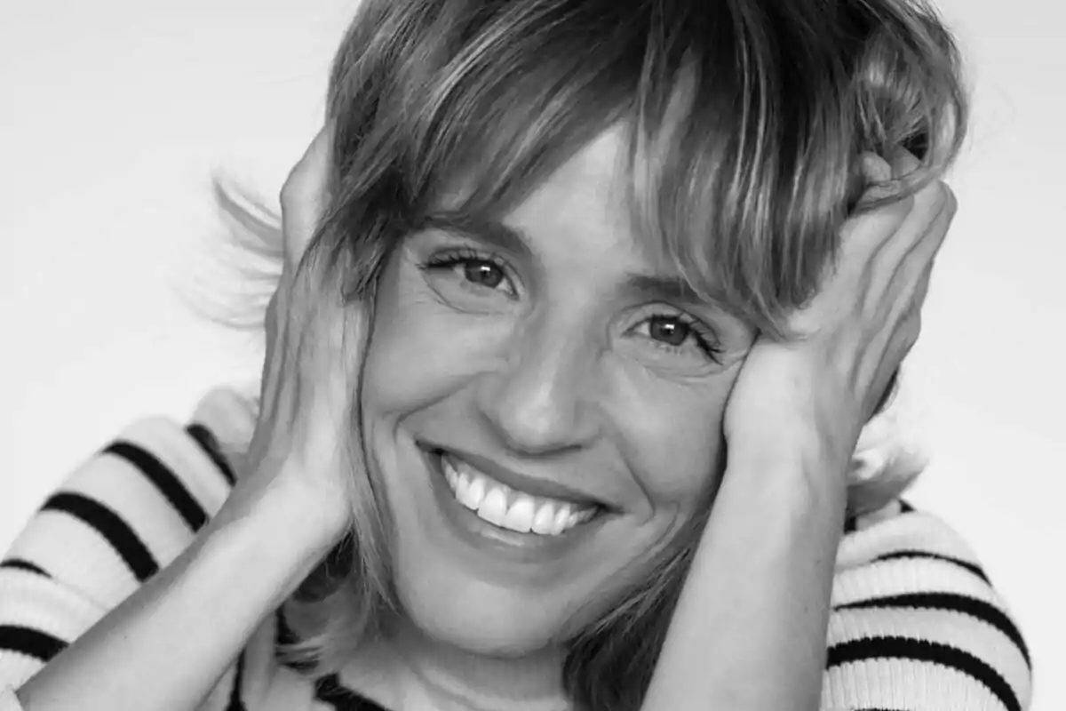 Mujer sonriendo con las manos en la cabeza en una fotografía en blanco y negro. Mujer sonriendo con las manos en la cabeza en una fotografía en blanco y negro.