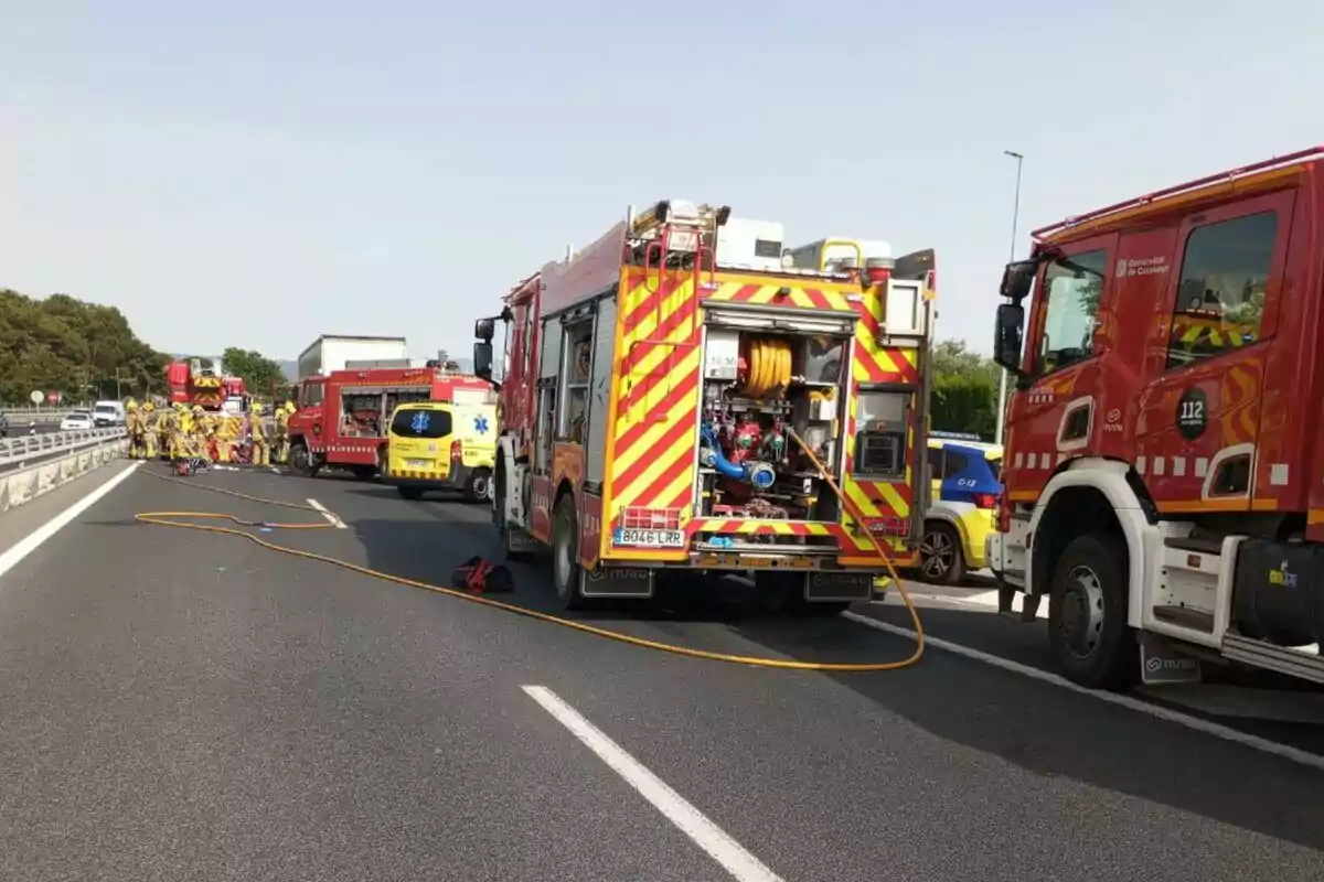 Un grupo de bomberos y vehículos de emergencia se encuentran en una autopista, aparentemente atendiendo una situación de emergencia.