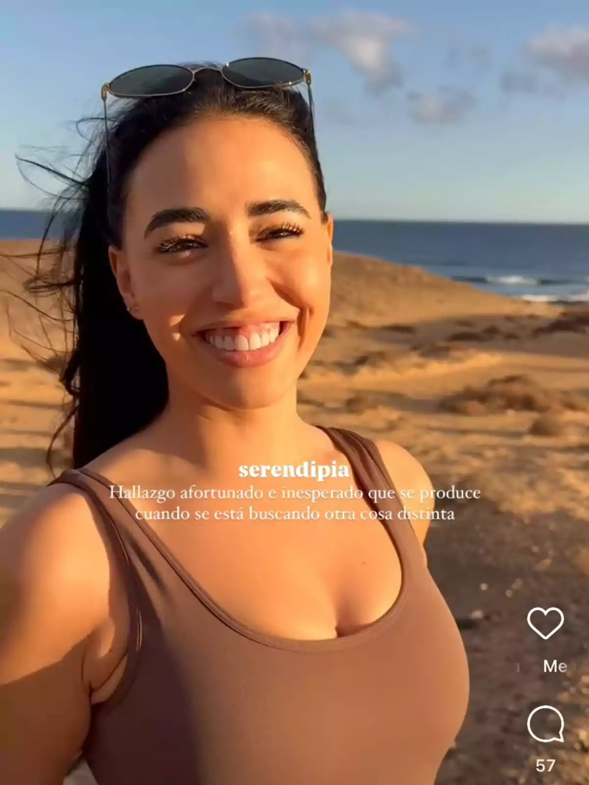 Carla Flila sonriente con gafas de sol en la cabeza está de pie en un paisaje costero con el mar y el cielo azul de fondo. Carla Flila sonriente con gafas de sol en la cabeza está de pie en un paisaje costero con el mar y el cielo azul de fondo.