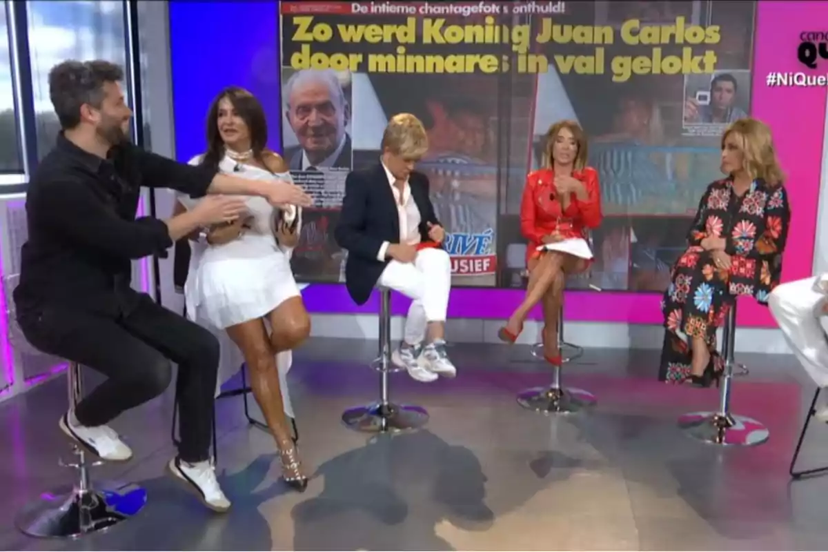 Los colaboradores de ‘Ni que fuéramos’ sentados en taburetes en plató junto con Aída Nízar, con un fondo que muestra una portada de revista con un titular en neerlandés sobre el rey Juan Carlos. Los colaboradores de ‘Ni que fuéramos’ sentados en taburetes en plató junto con Aída Nízar, con un fondo que muestra una portada de revista con un titular en neerlandés sobre el rey Juan Carlos.