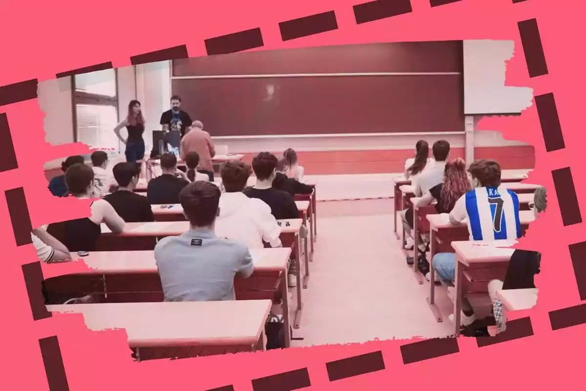 Un grupo de estudiantes sentados en pupitres dentro de un aula mientras observan a tres personas de pie frente al pizarrón.