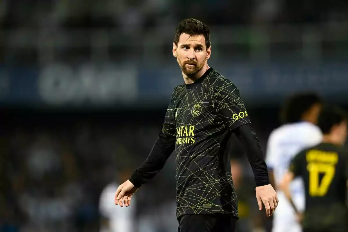 Un jugador de fútbol con uniforme negro y detalles dorados está en el campo durante un partido. Un jugador de fútbol con uniforme negro y detalles dorados está en el campo durante un partido.