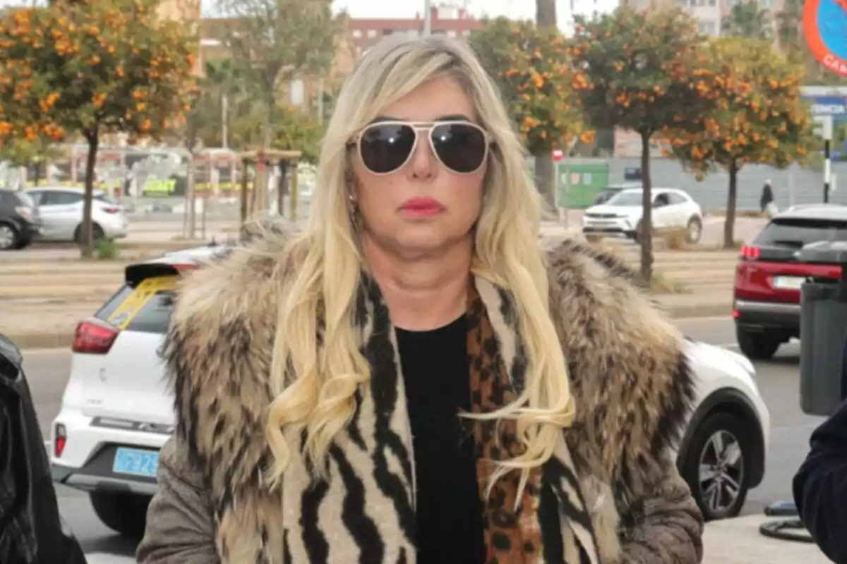 Plano medio de Malena Gracia con gafas de sol y abrigo de piel parada en una calle con árboles y coches de fondo. Plano medio de Malena Gracia con gafas de sol y abrigo de piel parada en una calle con árboles y coches de fondo.