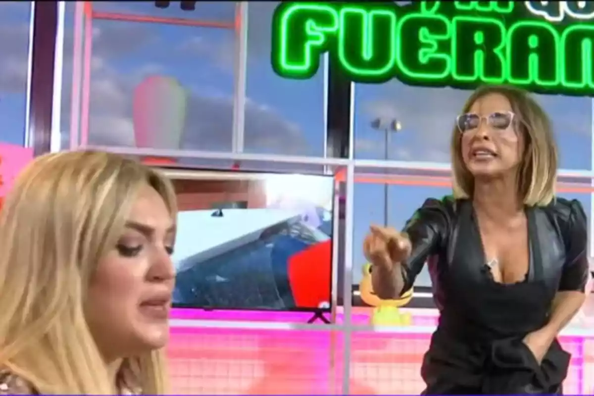 María Patiño y Marta Riesco discuten en un set de televisión con un letrero verde brillante en el fondo.