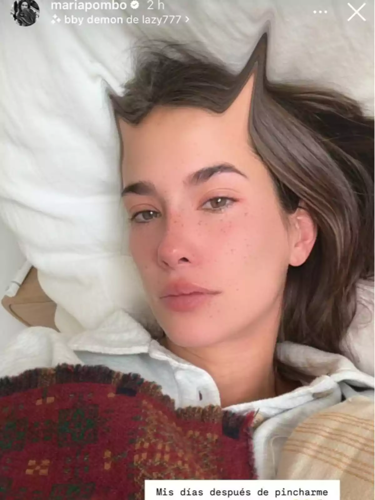 María Pombo acostada en la cama con un filtro que distorsiona su frente, cubierta con una manta de colores. María Pombo acostada en la cama con un filtro que distorsiona su frente, cubierta con una manta de colores.