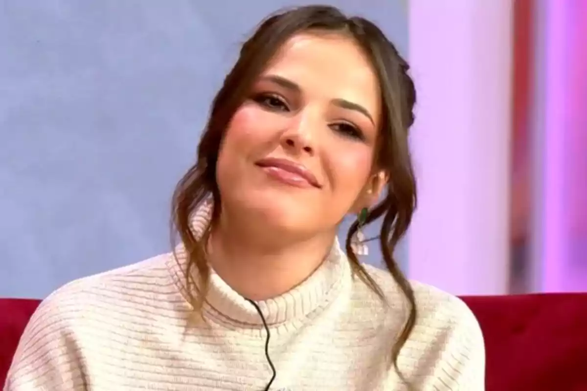 Marta Peñate con cabello castaño y suéter claro sonríe mientras está sentada en un entorno interior.