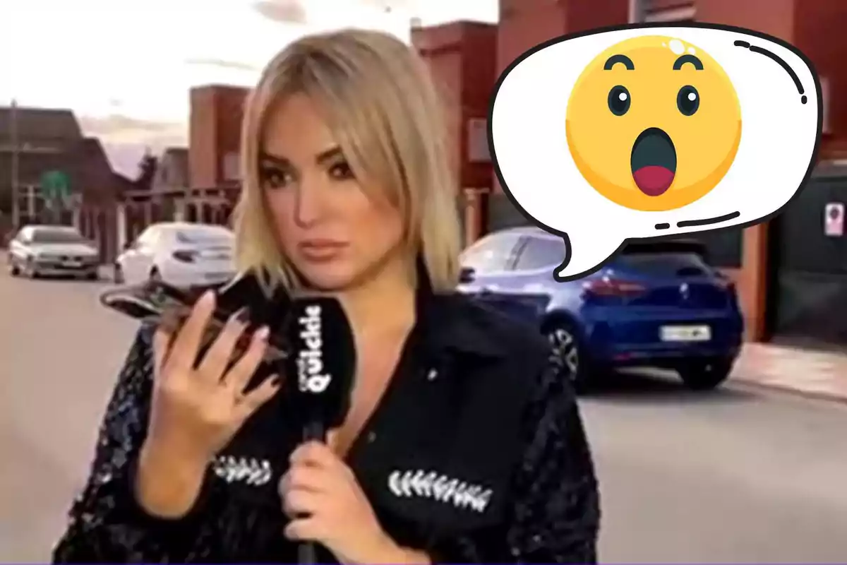 Marta Riesco sostiene un micrófono y un teléfono en la mano mientras está de pie en una calle con coches estacionados y un emoji de sorpresa en un globo de diálogo.