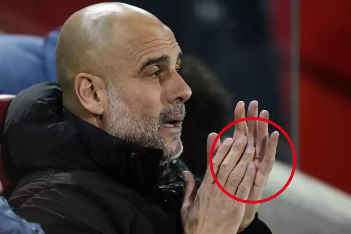 Un hombre calvo con barba aplaudiendo, con un anillo en el dedo anular de su mano izquierda, resaltado por un círculo rojo. Un hombre calvo con barba aplaudiendo, con un anillo en el dedo anular de su mano izquierda, resaltado por un círculo rojo.