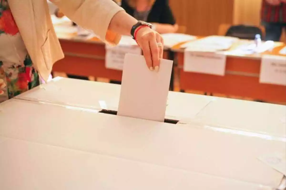Imagen de una persona introduciendo una carta de una votación en una urna
