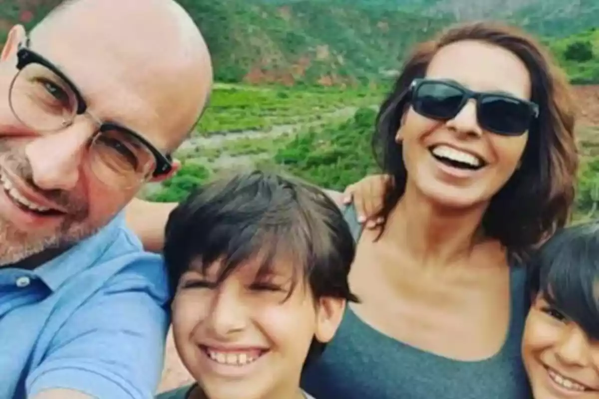 Una familia sonriente se toma una selfie al aire libre con un paisaje verde de fondo. Una familia sonriente se toma una selfie al aire libre con un paisaje verde de fondo.