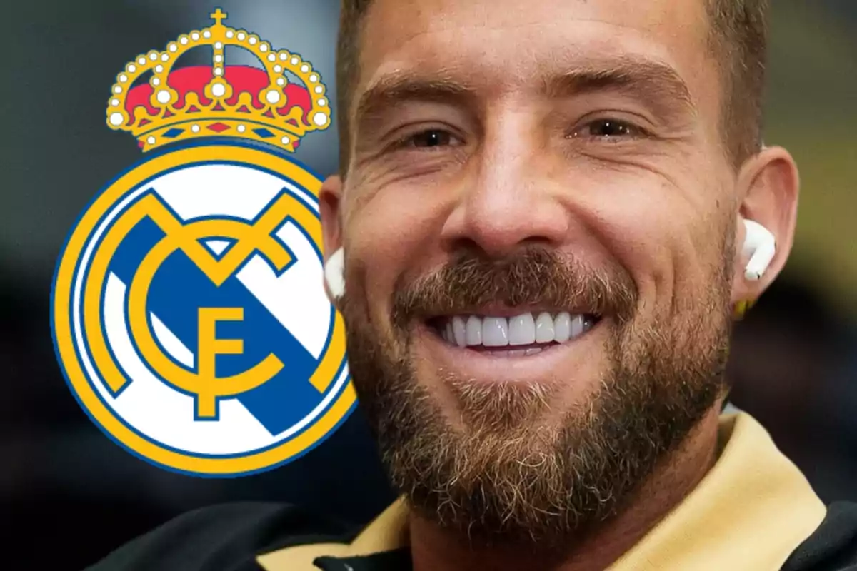 Hombre sonriente con auriculares y el escudo del Real Madrid al fondo.