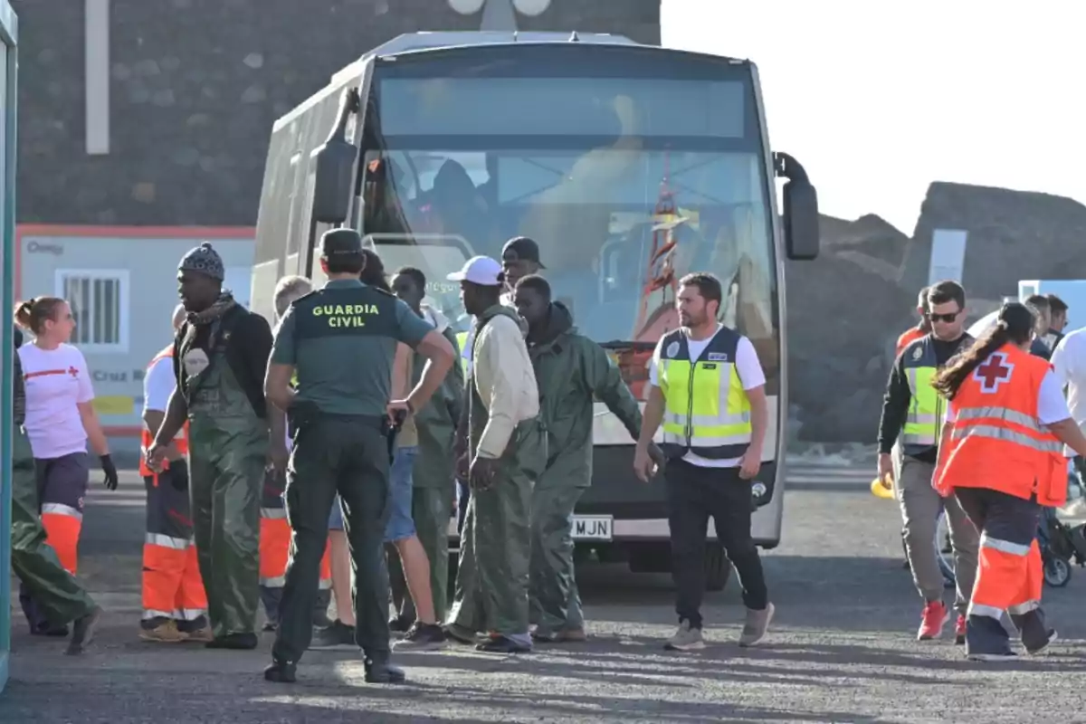 Un grupo de personas, incluyendo miembros de la Guardia Civil y de la Cruz Roja, se encuentran alrededor de un autobús.