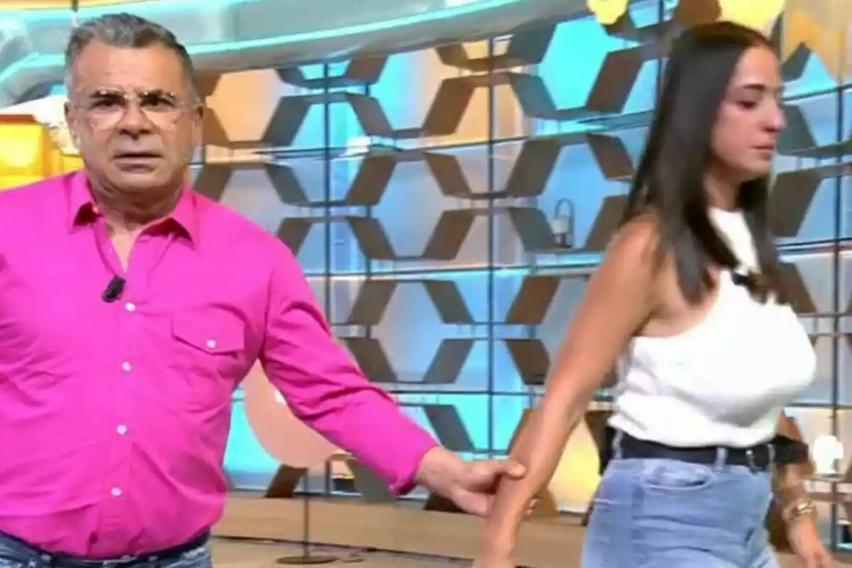 Jorge Javier Vázquez con camisa rosa sostiene el brazo de una mujer con camiseta blanca en el plató de El Diario de Jorge