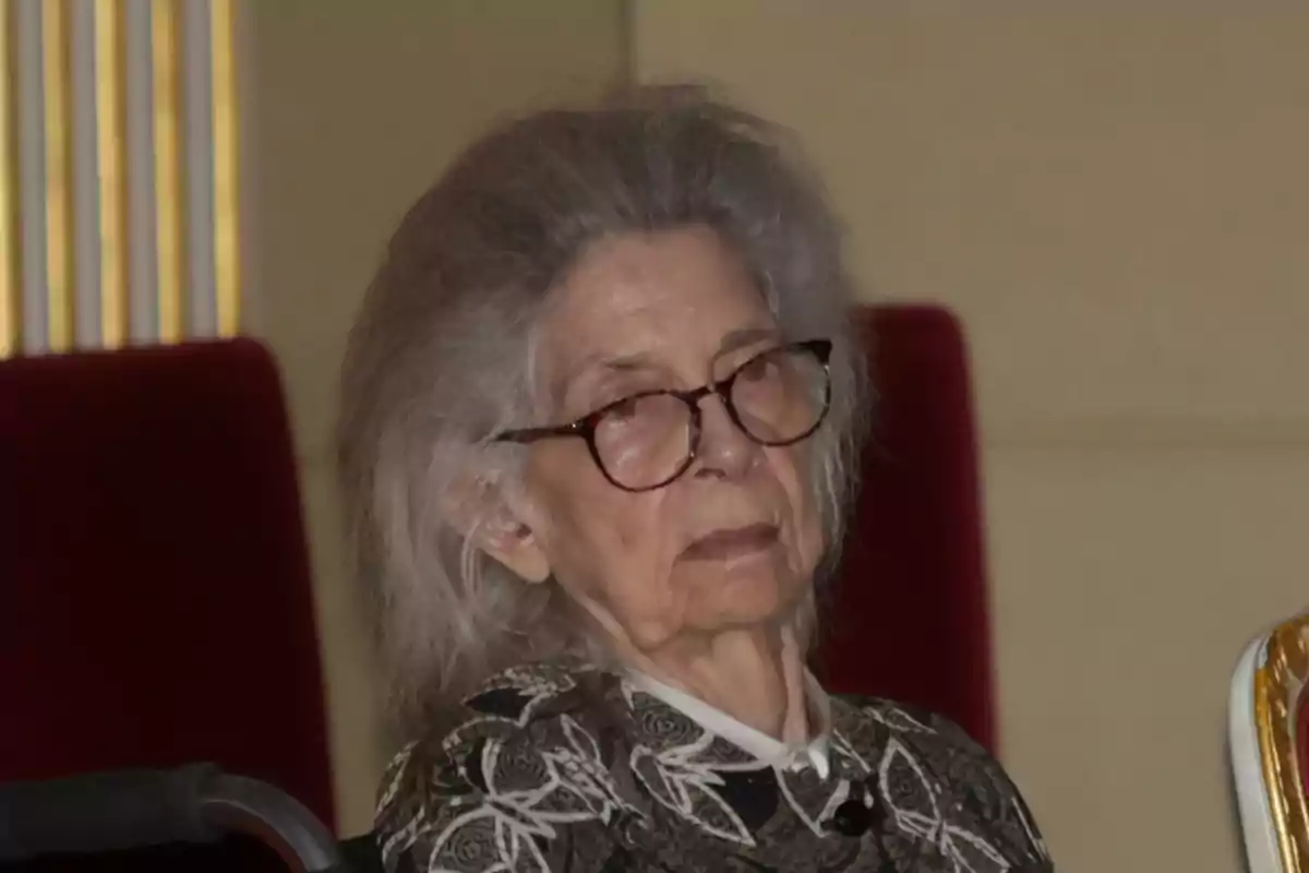 La princesa Irene de Grecia con gafas y cabello canoso sentada en una silla roja La princesa Irene de Grecia con gafas y cabello canoso sentada en una silla roja