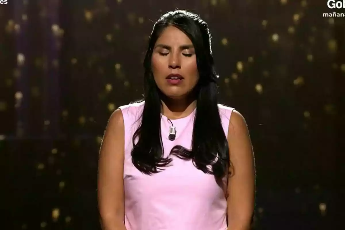 Isa Pantoja con vestido rosa y cabello largo oscuro con los ojos cerrados en el plató de De Viernes.