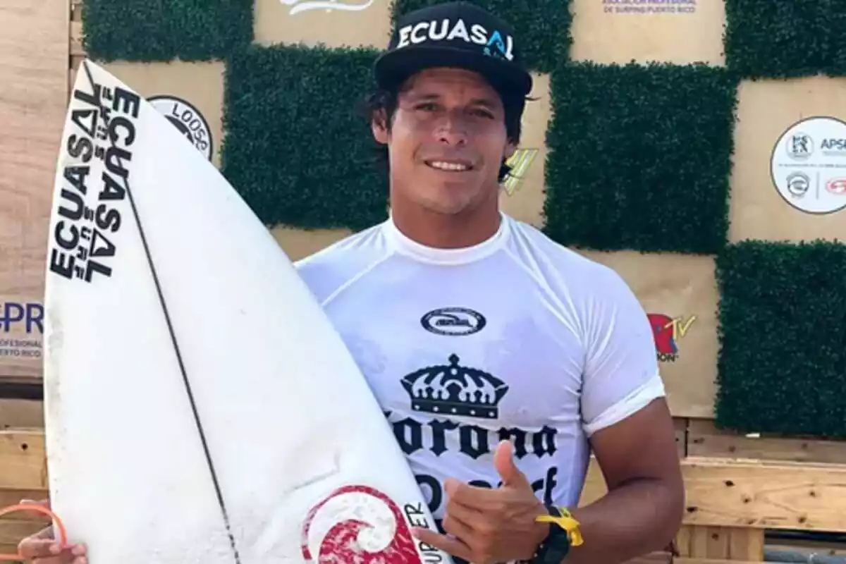 Israel Barona posando con una tabla de surf