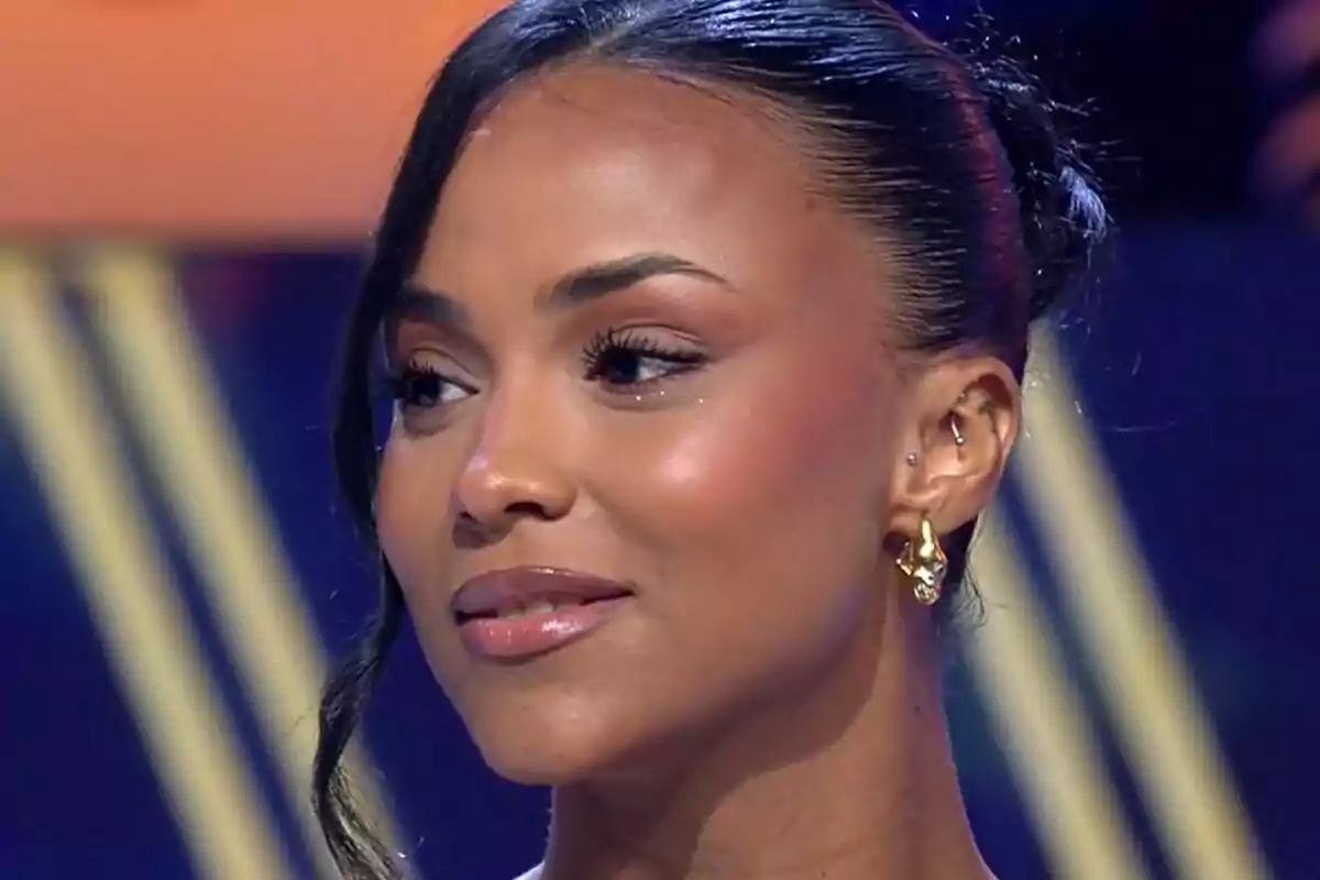 Jeimy Báez con cabello recogido y aretes dorados en un entorno iluminado en De Viernes.