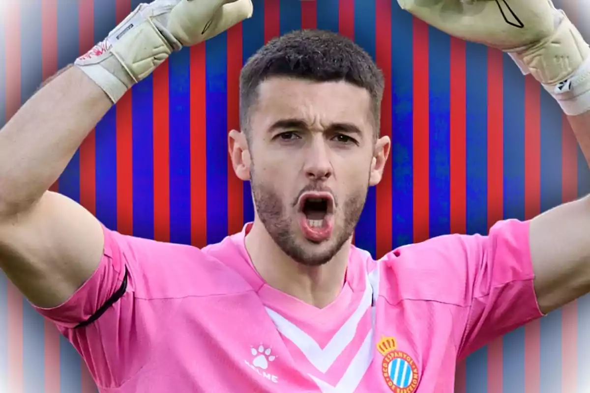 Un jugador de fútbol con uniforme rosa y guantes levanta los brazos frente a un fondo de rayas azules y rojas.