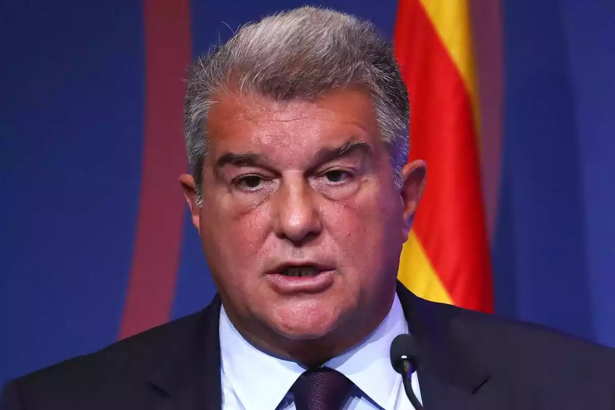 Joan Laporta con expresión seria en un primer plano con una bandera de fondo