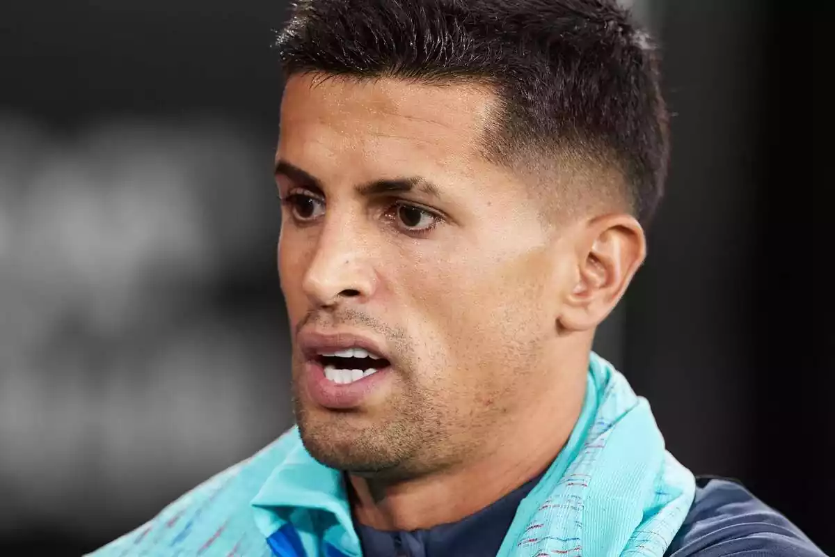 Joao Cancelo con cara de susto sobre un fondo blanco y negro