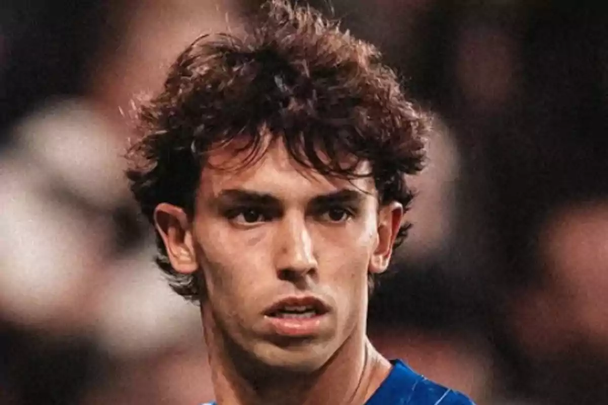 Un hombre con cabello rizado y expresión seria, vistiendo una camiseta azul, en un entorno desenfocado. Un hombre con cabello rizado y expresión seria, vistiendo una camiseta azul, en un entorno desenfocado.