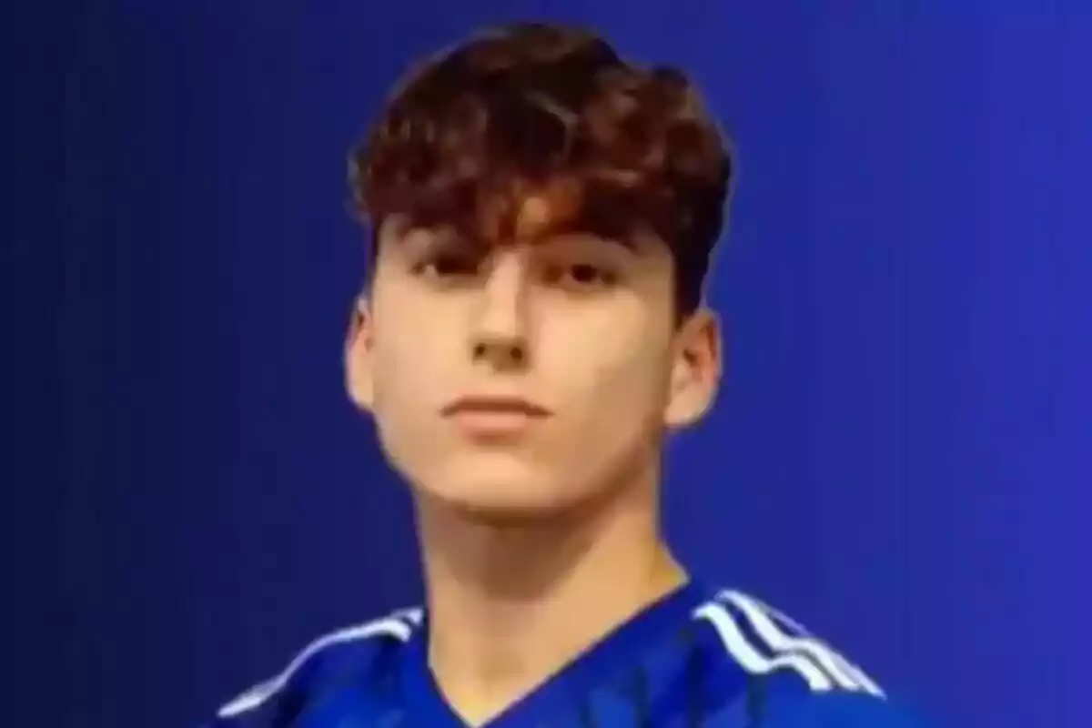 Un joven con cabello rizado y una camiseta azul con rayas blancas sobre un fondo azul. Un joven con cabello rizado y una camiseta azul con rayas blancas sobre un fondo azul.