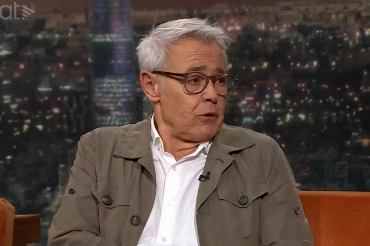 Jordi González de cabello canoso y gafas sentado en un set de televisión de Col·lapse con fondo de ciudad iluminada
