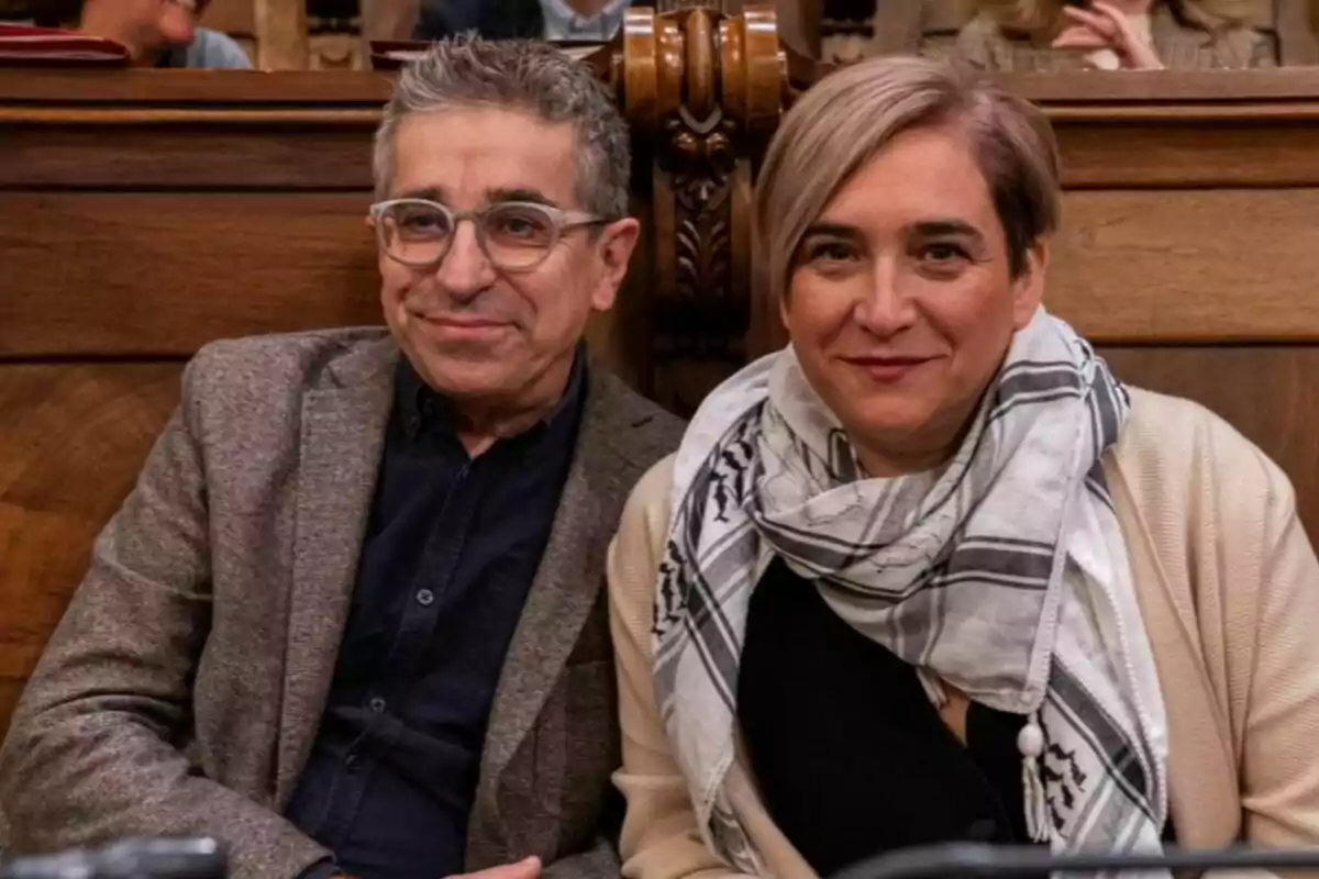 Dos personas sentadas en un banco de madera, una de ellas lleva gafas y la otra una bufanda.