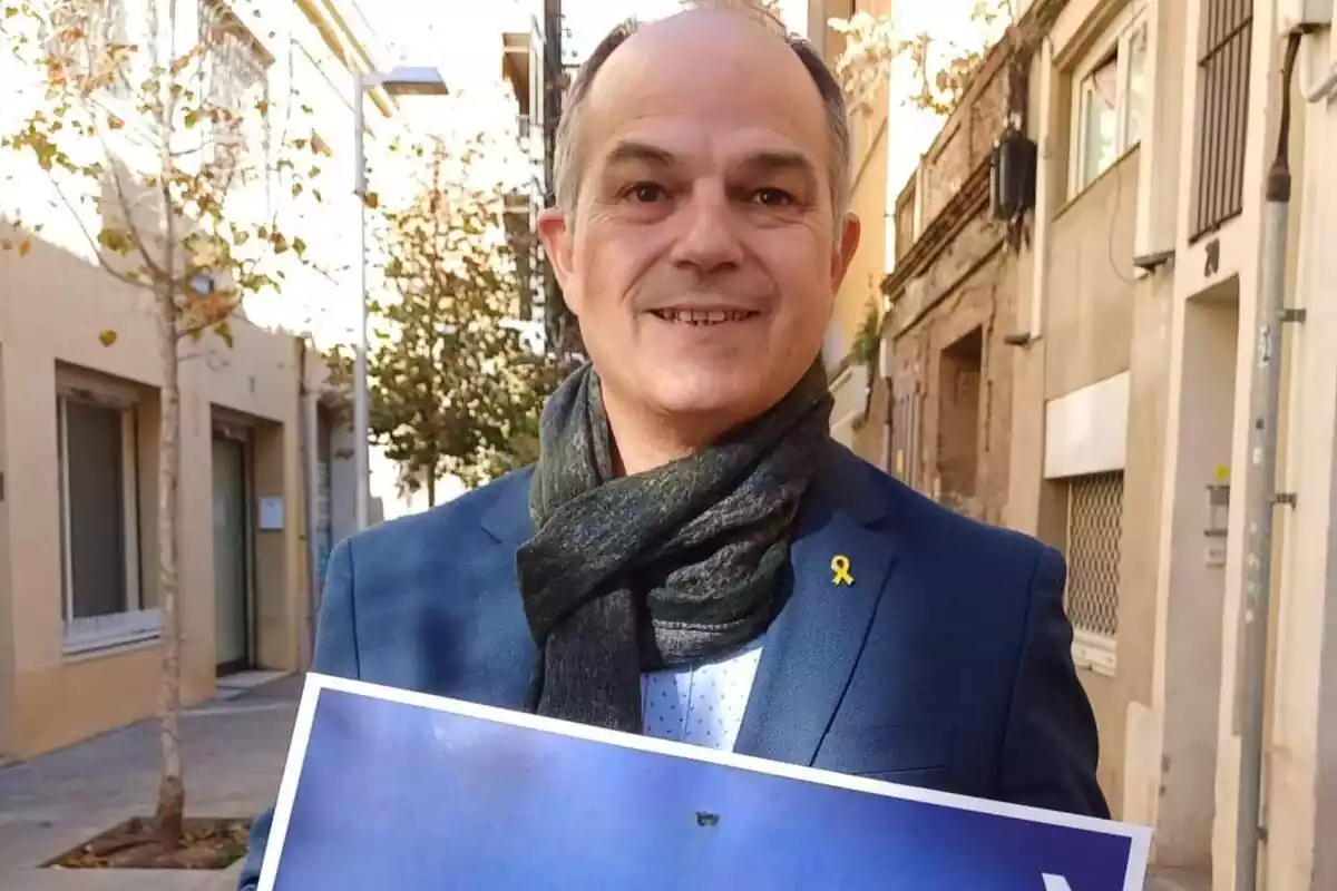 El político catalán Jordi Turull, muy sonriente, sosteniendo un cartel con las manos