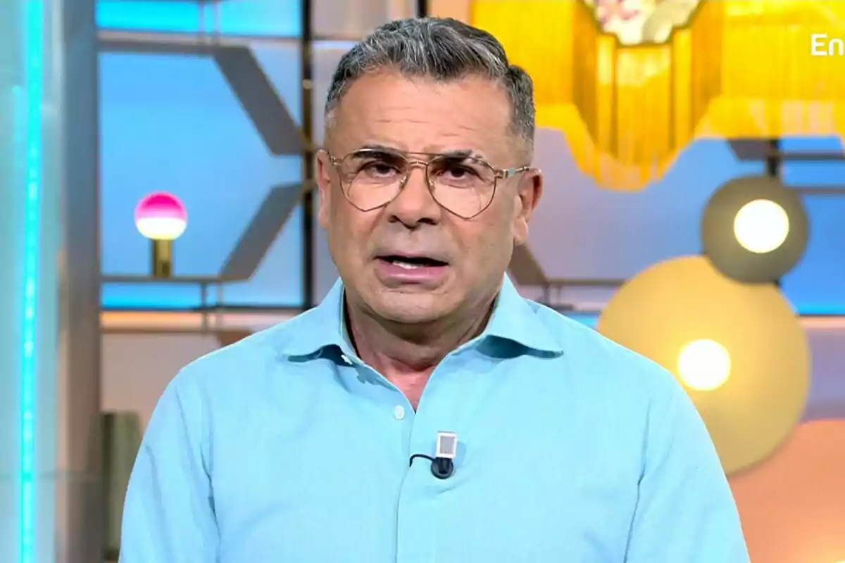 Jorge Javier Vázquez con gafas y camisa azul claro en un estudio de televisión con luces y decoraciones de fondo en El Diario de Jorge.