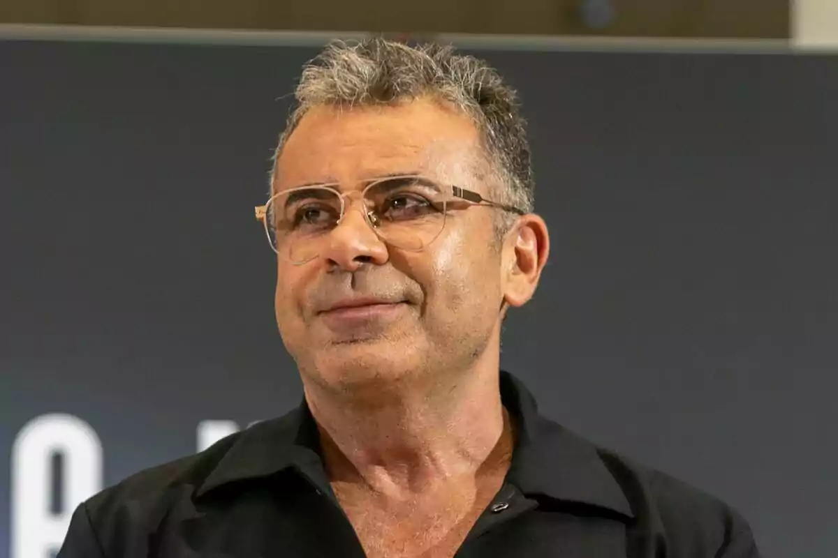 Jorge Javier Vázquez con edad con gafas y cabello canoso, vestido con una camisa negra, mirando hacia un lado con una expresión neutral durante la presentación de Gran Hermano en el FesTVal.