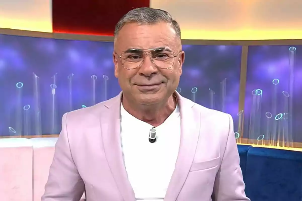 Captura de Jorge Javier Vázquez con gafas y chaqueta rosa claro, de pie en el plató de El Diario de Jorge con fondo azul y luces.