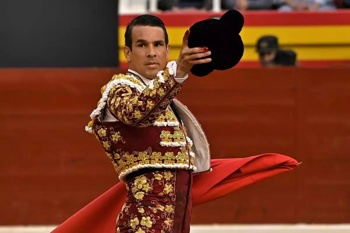 José María Manzanares con un traje de torero rojo y un sombrero en la mano José María Manzanares con un traje de torero rojo y un sombrero en la mano