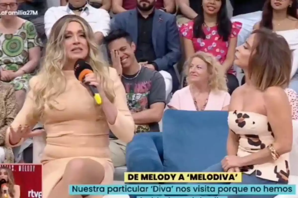La imitación de Melody y María Patiño conversan en 'La familia de la tele' con público al fondo, una de ellas sostiene un micrófono y la otra la observa atentamente mientras varias personas en la audiencia sonríen. La imitación de Melody y María Patiño conversan en 'La familia de la tele' con público al fondo, una de ellas sostiene un micrófono y la otra la observa atentamente mientras varias personas en la audiencia sonríen.