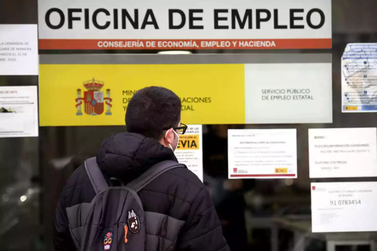 Un joven leyendo unos carteles informativos expuestos en una oficina del SEPE