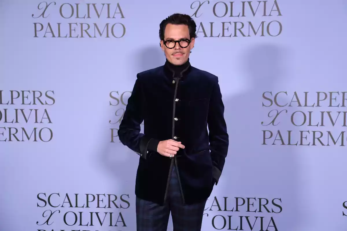 Juan Avellaneda con gafas y bigote lleva un traje oscuro frente a un fondo que dice Juan Avellaneda con gafas y bigote lleva un traje oscuro frente a un fondo que dice