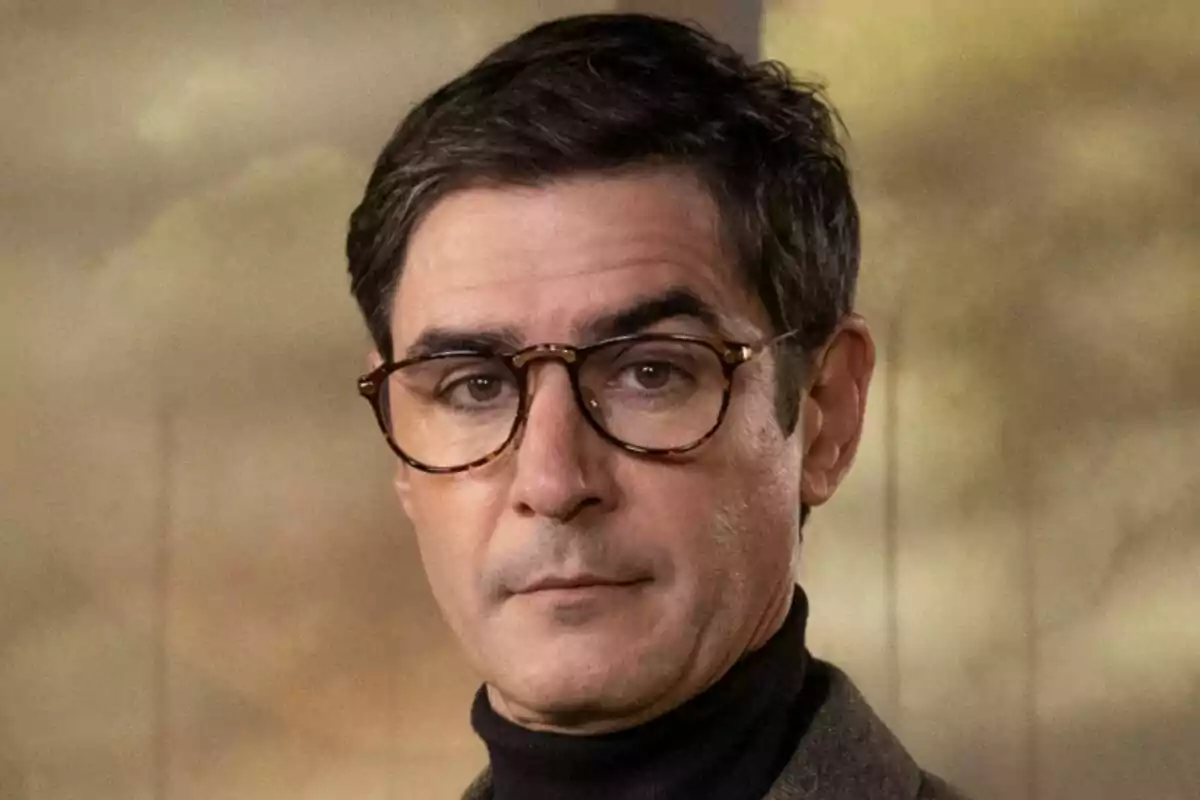 Juanra Bonet con gafas y cabello oscuro mira a la cámara con una expresión seria en Traitors.
