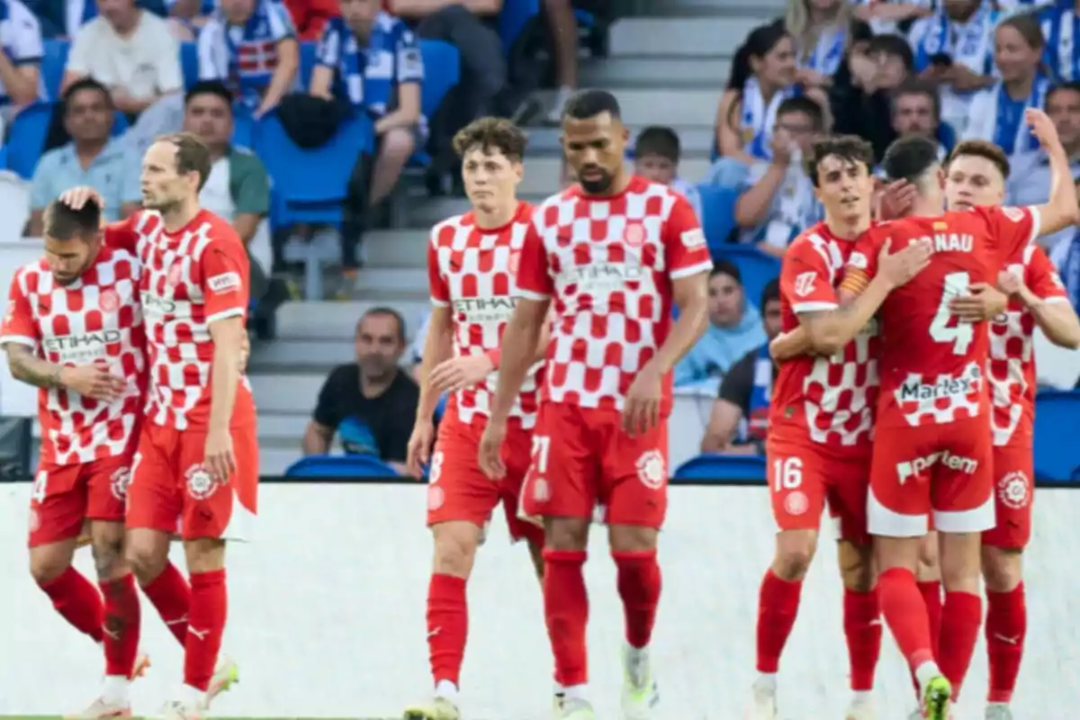 Jugadores de un equipo de fútbol con uniforme rojo y blanco celebran en el campo mientras el público observa desde las gradas Jugadores de un equipo de fútbol con uniforme rojo y blanco celebran en el campo mientras el público observa desde las gradas