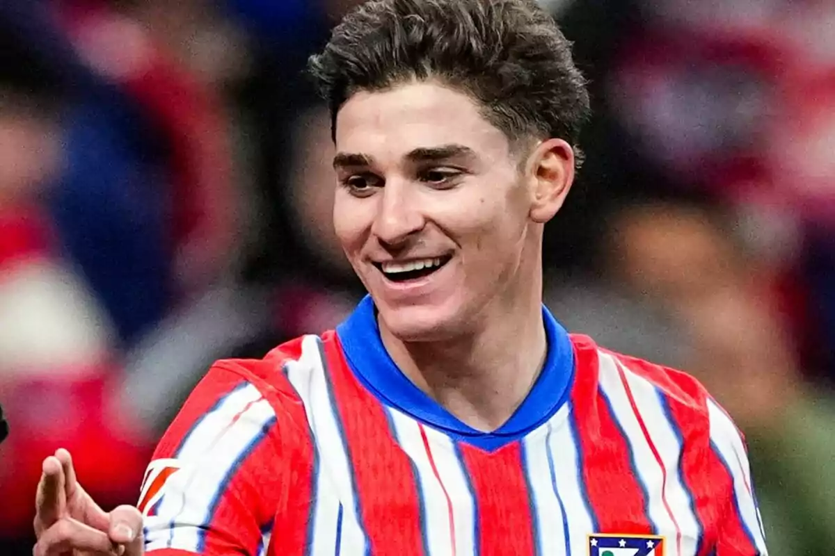 Un jugador de fútbol sonríe mientras lleva una camiseta a rayas rojas y blancas. Un jugador de fútbol sonríe mientras lleva una camiseta a rayas rojas y blancas.