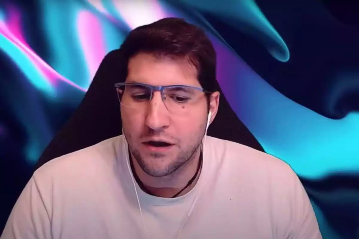 Captura del canal de youtube de Julián Contreras donde se le ve sentado con gafas y auriculares mirando hacia abajo y hablando sobre un fondo iluminado