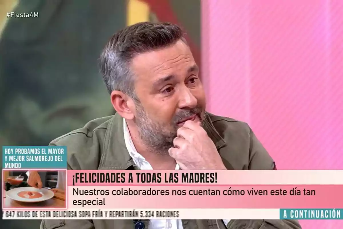 Kike Calleja con barba y cabello canoso aparece en Fiesta, con un fondo rosa y texto en pantalla que felicita a las madres y menciona una degustación de salmorejo. Kike Calleja con barba y cabello canoso aparece en Fiesta, con un fondo rosa y texto en pantalla que felicita a las madres y menciona una degustación de salmorejo.