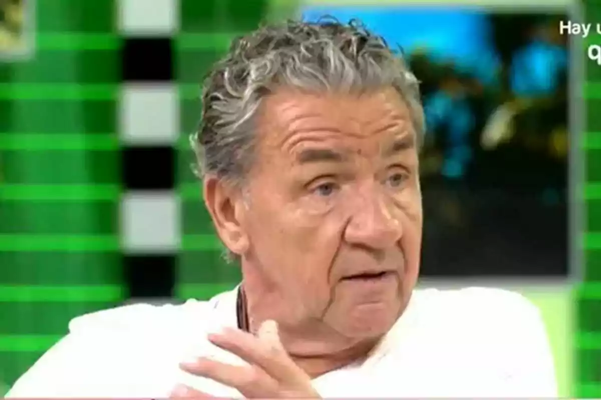 Koldo Royo de cabello canoso y rizado con camiseta blanca hablando en un set de Fiesta con fondo verde Koldo Royo de cabello canoso y rizado con camiseta blanca hablando en un set de Fiesta con fondo verde
