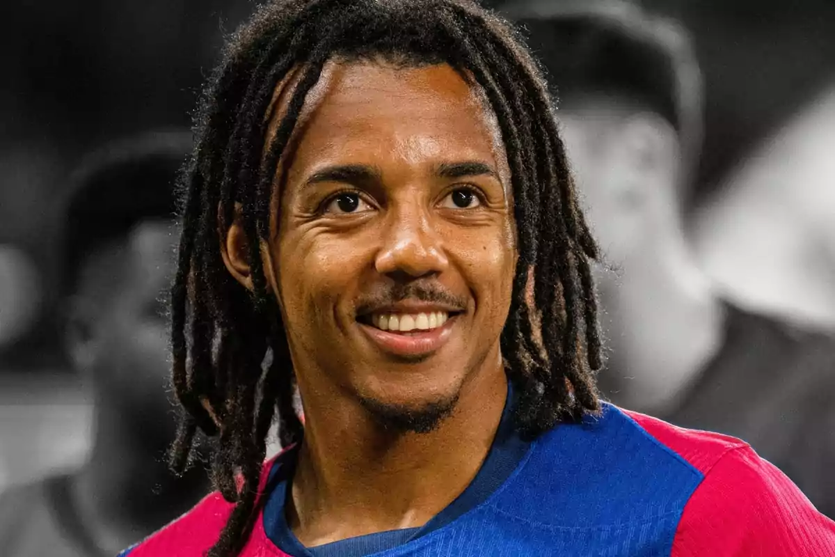 Jugador de fútbol con camiseta azul y roja sonriendo y con el cabello en rastas