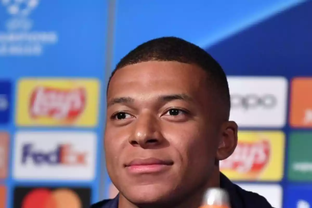 Un hombre en una conferencia de prensa con un fondo de logotipos de marcas. Un hombre en una conferencia de prensa con un fondo de logotipos de marcas.